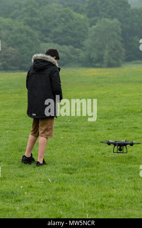 Biracial boy vola drone a Weald Country Park modello di rilascio trattenuto Foto Stock