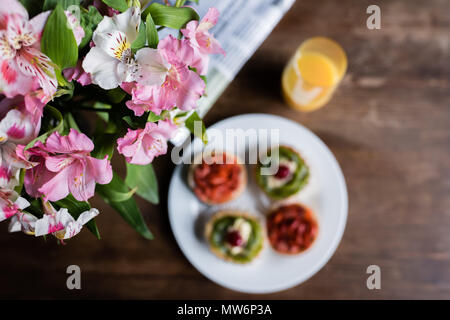 Natura morta di fiori, quotidiano, prima colazione con torte e bicchiere di succo di frutta sul tavolo della cucina Foto Stock