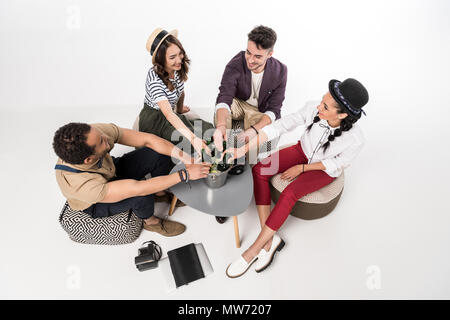 Angolo di alta vista di felice giovani amici seduti insieme a tavola con bottiglie di birra nel secchio ed elettronica Foto Stock