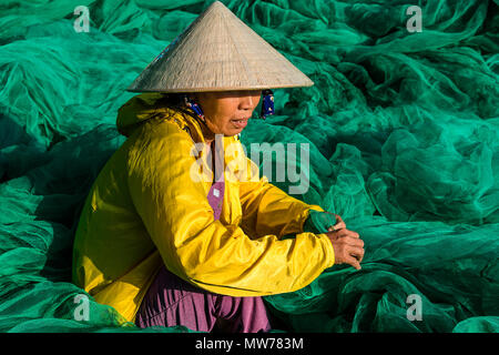 Donna tessitura di reti da pesca al di fuori della sua casa nel Mui Ne, Vietnam Foto Stock