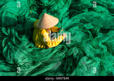 Donna tessitura di reti da pesca al di fuori della sua casa nel Mui Ne, Vietnam Foto Stock