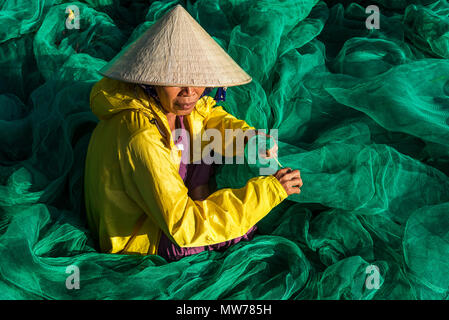 Donna tessitura di reti da pesca al di fuori della sua casa nel Mui Ne, Vietnam Foto Stock