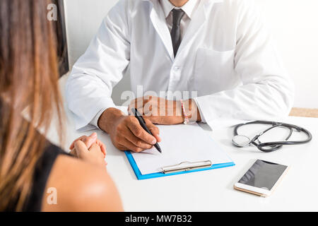 Il medico e il paziente stanno discutendo circa la diagnosi. Medico tenendo uno stetoscopio e prendere appunti. Foto Stock