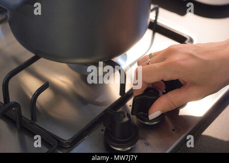 Donna a mano apertura di combustione di gas da cucina fornello a gas. Foto Stock