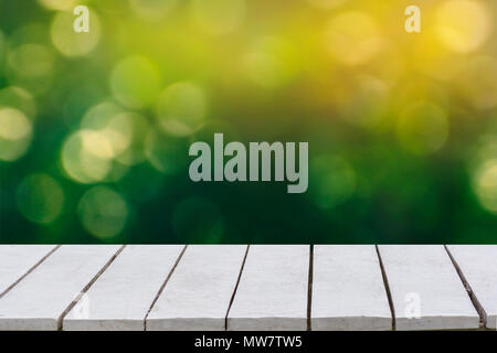 Verde naturale lo sfondo con il fuoco selettivo. Lo sfondo verde ha un bokeh di foglie ed erba su un bianco con pavimento in legno. Foto Stock