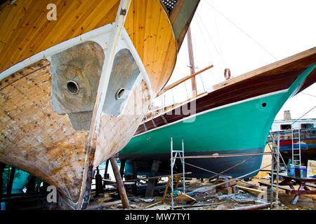 Cantiere navale contenente due navi in legno per la riparazione e il rinnovo di lavori di verniciatura a scafi, Cipro settentrionale. Foto Stock