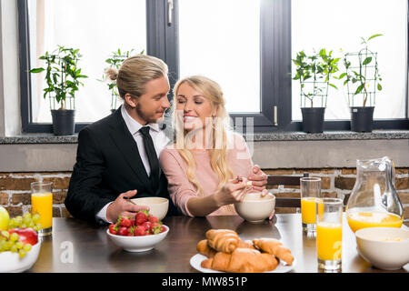 Sorridente giovane imprenditore con bella moglie felice di fare colazione insieme a casa Foto Stock