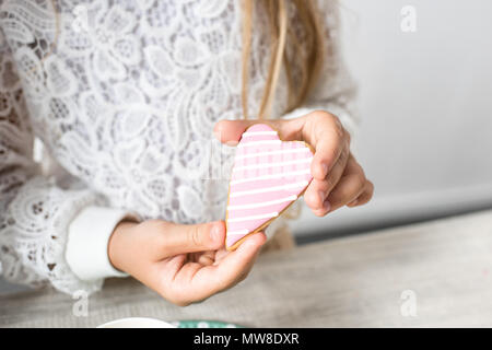 Ritagliato shot della ragazza di contenimento a forma di cuore cookie alla festa di compleanno Foto Stock