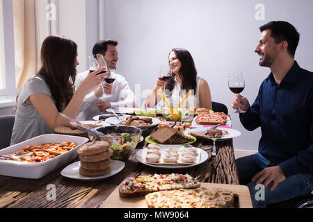 Sorridente giovani amici gustando cibo con un bicchiere di vino al ristorante Foto Stock