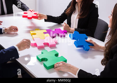 Gruppo di imprenditori risolvere colorato Puzzle sulla scrivania Foto Stock