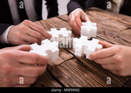 Gruppo di imprenditori risolvendo puzzle sulla scrivania Foto Stock