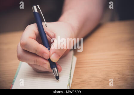 L uomo è la scrittura a mano su un blocco note con una penna, copywriting concept Foto Stock