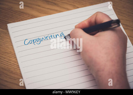 L uomo è la scrittura a mano su un blocco note con una penna, copywriting concept Foto Stock