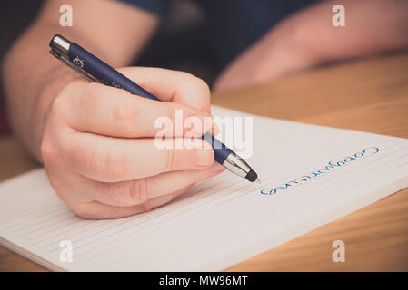 L uomo è la scrittura a mano su un blocco note con una penna, copywriting concept Foto Stock