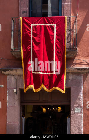 Rosso e oro banner è scesa dal balcone del levigatore della festa del Corpus Domini in San Miguel De Allende, Messico Foto Stock