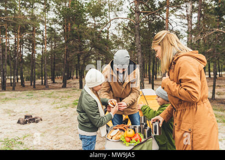 La famiglia felice avente picnic sulla natura in autunno freddo giorno Foto Stock