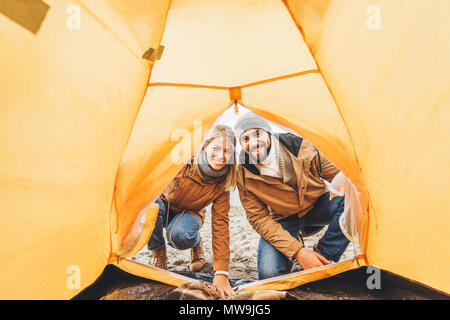 Felice bella giovane guardando tenda da campeggio Foto Stock