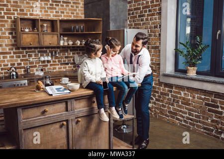 Padre e belle piccole figlie di trascorrere del tempo in cucina insieme Foto Stock