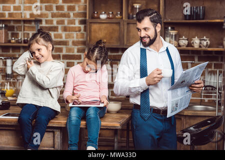 Giovane padre Felice e le figlie di trascorrere del tempo in cucina in mattinata Foto Stock