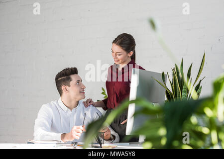 Giovani manager flirtare al posto di lavoro in un ufficio moderno Foto Stock