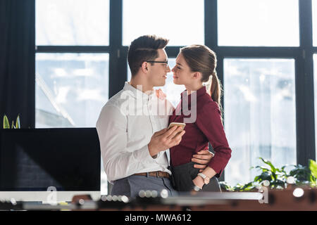 Attraente baciare i giovani imprenditori in abbigliamento formale avente carica romanticismo Foto Stock