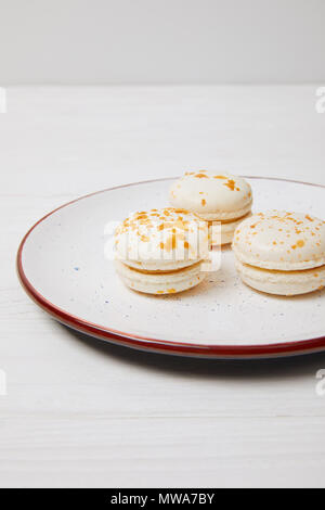 Tre macarons nella piastra su bianco tavolo in legno Foto Stock