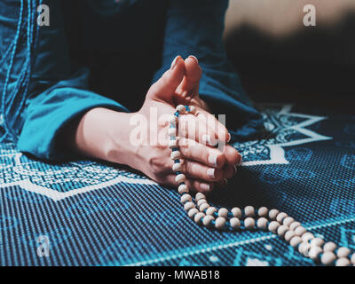 Concentrato di donna orante con il rosario in legno talloni sul materassino yoga con mandala. Namaste. Chiudere fino a mani. gratitudine concetto. Foto Stock