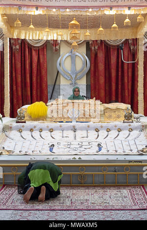 Una donna Sikh pregando di fronte una donna granthi al Gurdwara Sikh Società culturale nel sud Richmond Hill, Queens, a New York. Foto Stock