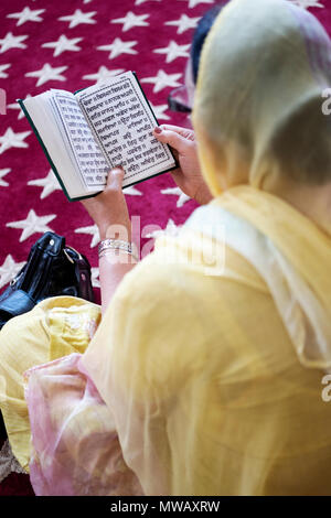 Una donna Sikh e il suo libro di preghiera scritta in Punjabi al Gurdwara Sikh Società culturale nel sud Richmond Hill, Queens, a New York. Foto Stock