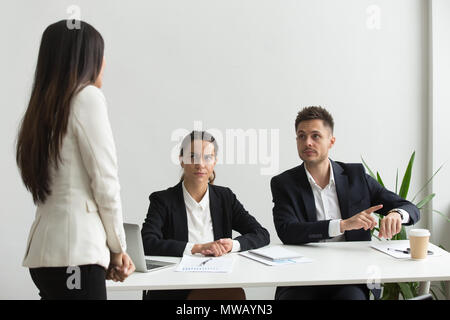 Arrabbiato executive rivolti a un orologio da polso scolding dipendente per bei Foto Stock