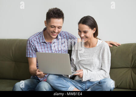 Felice coppia giovane ridere mentre si effettua chiamata video su laptop Foto Stock