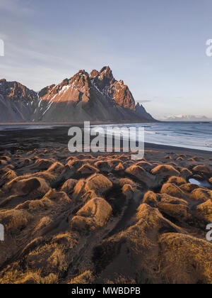 Spiaggia di sabbia nera, ricoperta di pietre, montagne, Klifatindur Eystrahorn e Kambhorn, la Capezzagna Stokksnes, massiccio Klifatindur Foto Stock