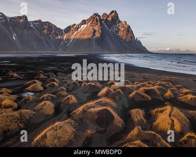 Spiaggia di sabbia nera, ricoperta di pietre, montagne, Klifatindur Eystrahorn e Kambhorn, la Capezzagna Stokksnes, massiccio Klifatindur Foto Stock