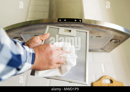 Uomo di pulizia delle mani in maglia di alluminio filtro per cappa. I lavori domestici e di faccende. Cucina cappa sullo sfondo Foto Stock