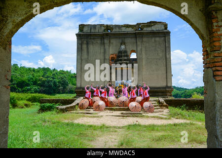 Kanchanaburi, Tailandia - 24 Luglio 2016: belle ragazze adolescenti con Mon tradizione abiti danza per mostrare i turisti vicino alla rovina Chiesa buddista in Foto Stock