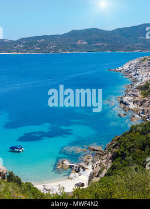 Estate sunshiny panorama del mare con barca in acquamarina di acqua trasparente e la spiaggia di sabbia. Vista dalla riva (, Sithonia Halkidiki, Grecia). Foto Stock