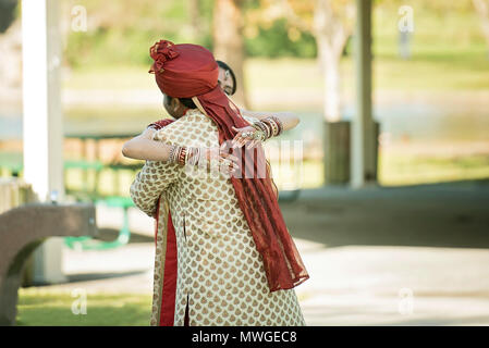 Indian lo sposo abbraccia la sposa nel parco Foto Stock