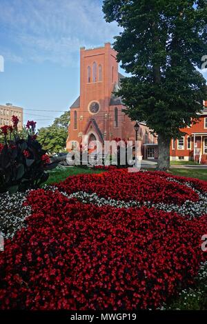 Charlottetown, Prince Edward Island, Canada: Anglicana, la Cattedrale di San Pietro (1869), dietro il luminoso rosso dei fiori di Rochford Square. Foto Stock