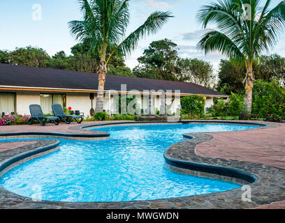 Vuoto motel all'aperto piscina con sedie a sdraio e Moai teste, Hotel Puku Vai, Hanga Roa, Isola di Pasqua, Rapa Nui, Cile Foto Stock