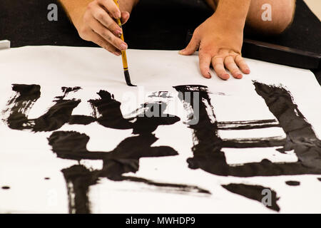 Un uomo che pratica la calligrafia giapponese. Foto Stock