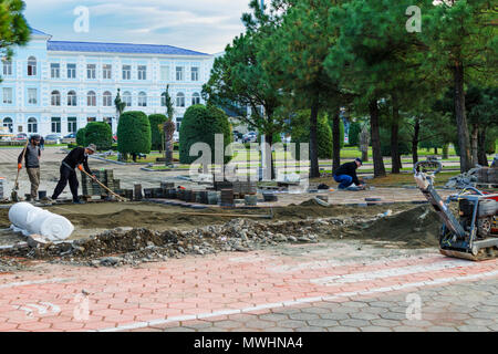 Batumi, Georgia, 2017-11-28: Lavoro laici costruttori nuova pavimentazione lastra sulla zona pedonale, marciapiede tra parco nella città. Utilizzo di utensili a mano per il livellamento del terreno Foto Stock