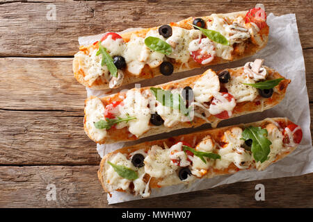 Hot gustoso taglio baguette cotta con pollo, formaggio, pomodori, olive e funghi vicino sul tavolo. parte superiore orizzontale vista da sopra Foto Stock