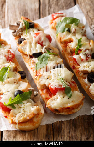 Aprire il panino caldo baguette pizza in casseruola con pollo, formaggio, pomodori, olive e funghi sulla tavola verticale. Foto Stock