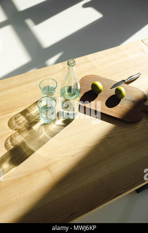 Vista aerea del limes sulla tavola di legno e acqua in bicchieri e bottiglia sul tavolo di legno Foto Stock