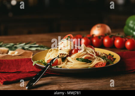 Tradizionale pasta italiana con pomodori e rucola nella piastra con forca Foto Stock