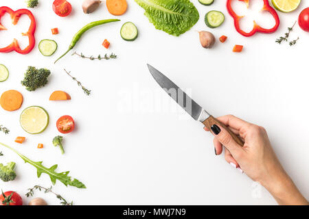 Immagine ritagliata della donna che mantiene il coltello sopra la tabella con le verdure isolato su bianco Foto Stock