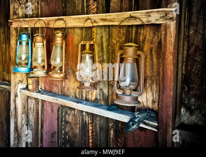 Vecchie lampade a olio usate in famiglie. Accessori per illuminare l'interno delle case, appesi in un vano di legno abbandonato. Foto Stock