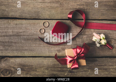 Lay piatto con gli anelli di nozze, portagioie, bridal bouquet e corpetto sul piano portapaziente in legno Foto Stock