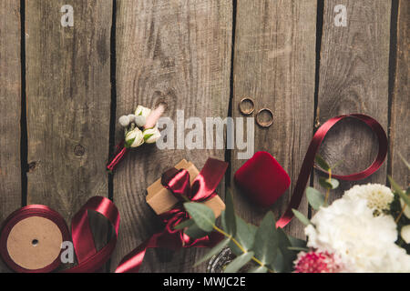 Lay piatto con gli anelli di nozze, portagioie, bridal bouquet e corpetto sul piano portapaziente in legno Foto Stock