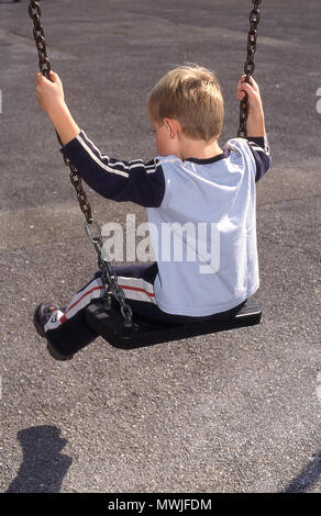 6 anno vecchio ragazzo su una swing (vista posteriore) Foto Stock